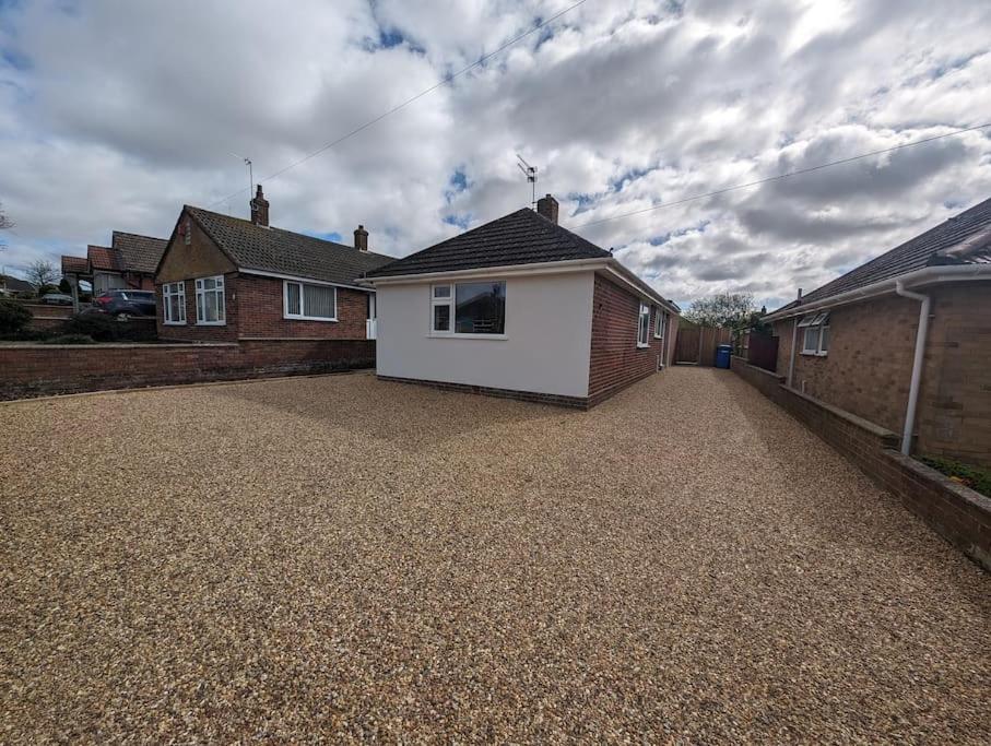 a house with a white garage on a gravel driveway at Clovelly Rise in Lowestoft