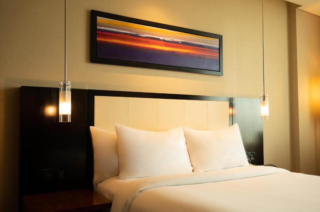 a bedroom with a white bed with a picture on the wall at DoubleTree by Hilton-Pune Chinchwad in Pune