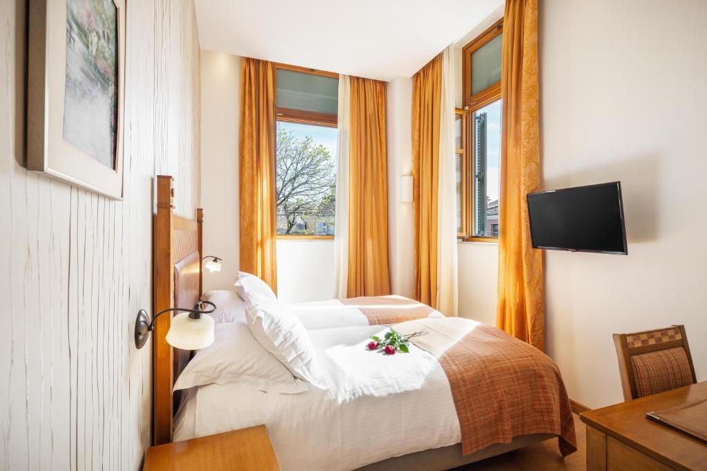 um quarto de hotel com duas camas e uma televisão em Bella Venezia em Corfu Town