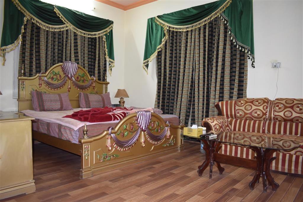 a bedroom with a bed and a couch and a chair at Islamabad Lodges in Islamabad