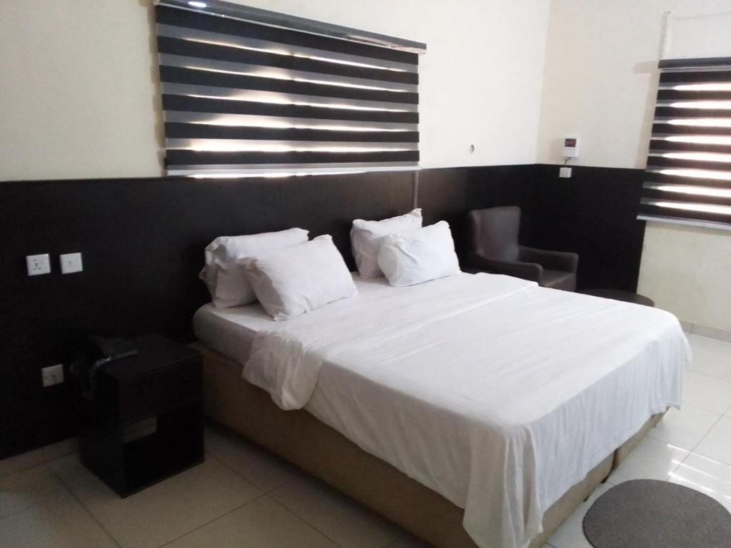 um quarto com uma cama com lençóis brancos e almofadas em st Theresers apartment B2 em Lekki