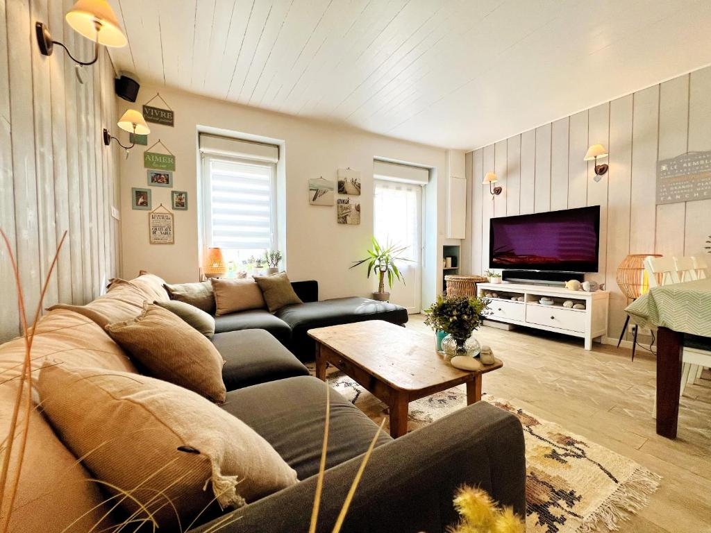 ein Wohnzimmer mit einem Sofa und einem TV in der Unterkunft La Maison de la Plage in Les Sables-dʼOlonne
