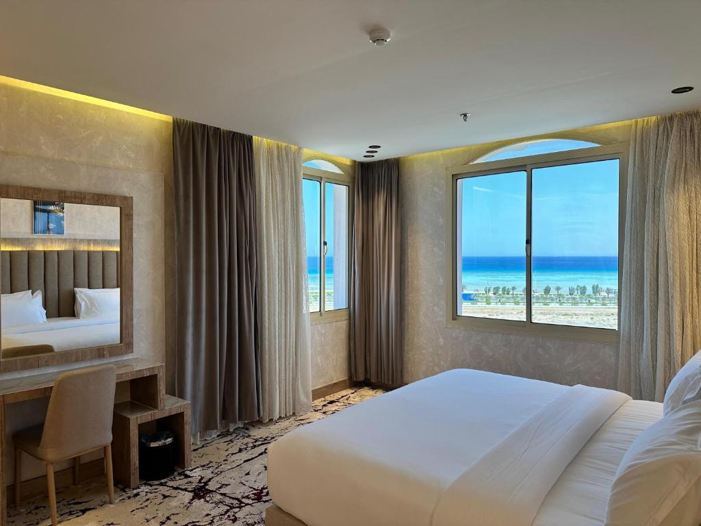 ein Hotelzimmer mit einem großen Bett und einem großen Fenster in der Unterkunft حياة تاون 3 in Umm Lajj
