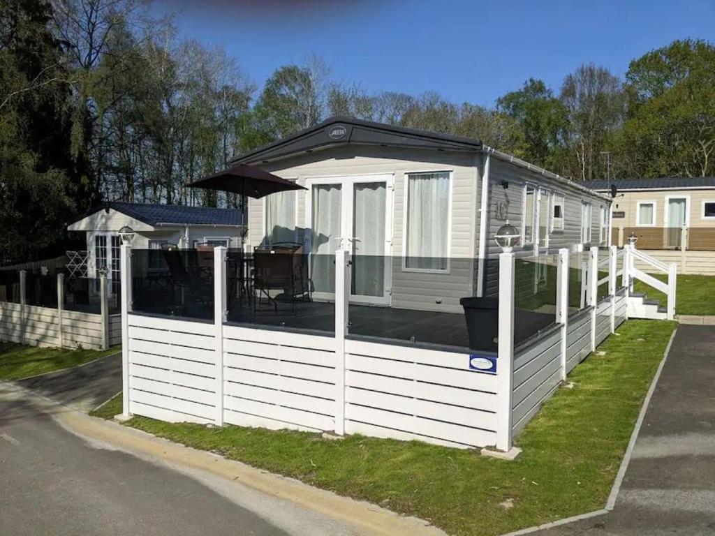 a tiny house with a white fence and an umbrella at The Willows - 3 bedrooms with enclosed decking in Fairlight