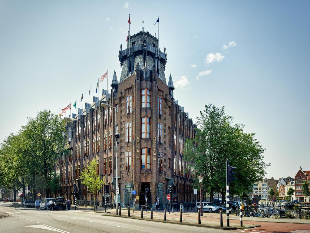 ein großes Gebäude mit einem Uhrturm auf einer Straße in der Unterkunft Grand Hotel Amrâth Amsterdam in Amsterdam