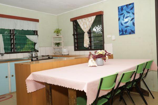 ギゾにあるGizo Lodgeのキッチン(テーブル、緑の椅子、カウンター付)