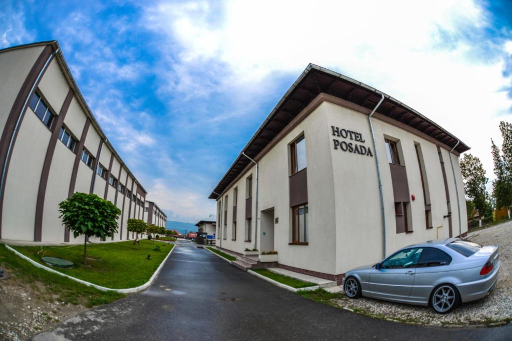 un coche aparcado frente a un edificio en Hotel Posada, en Râmnicu Vâlcea