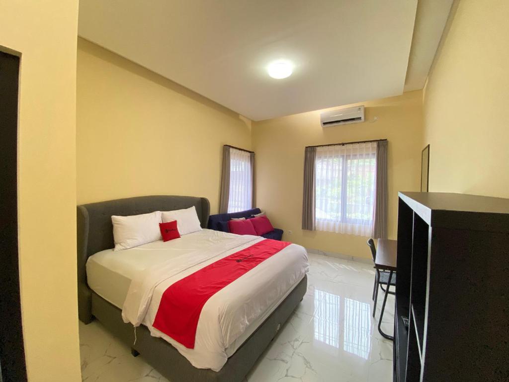 a bedroom with a bed with a red blanket at RedDoorz Syariah near Alun Alun Purwokerto 3 in Purwokerto