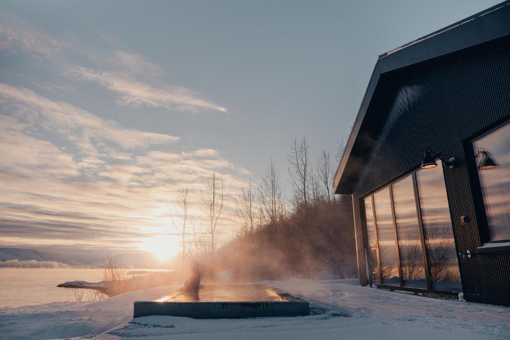 a building in the snow with the sun in the background at Svart Lodge in Akureyri