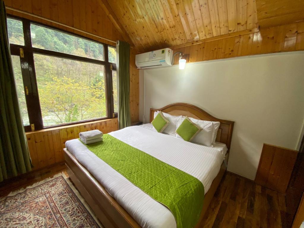 a bedroom with a bed with a green blanket at The River Front Luxury Cottage By Stay Pattern in Anantnāg