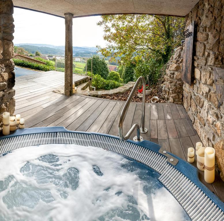 a jacuzzi tub in a garden with a wooden deck at Casa do Cebro Casa con piscina y jacuzzi privados in Santiago de Compostela