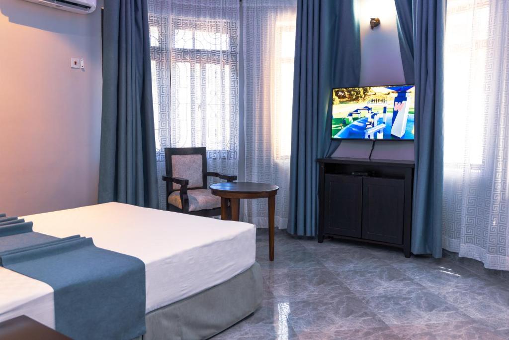 um quarto de hotel com uma televisão e uma cama em Velmont Hotel em Dar es Salaam