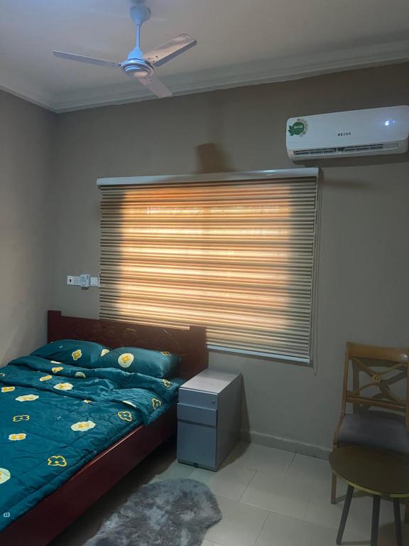 a bedroom with a bed and a window with a fan at Oyibi Saasabi Apartment in Oyibi
