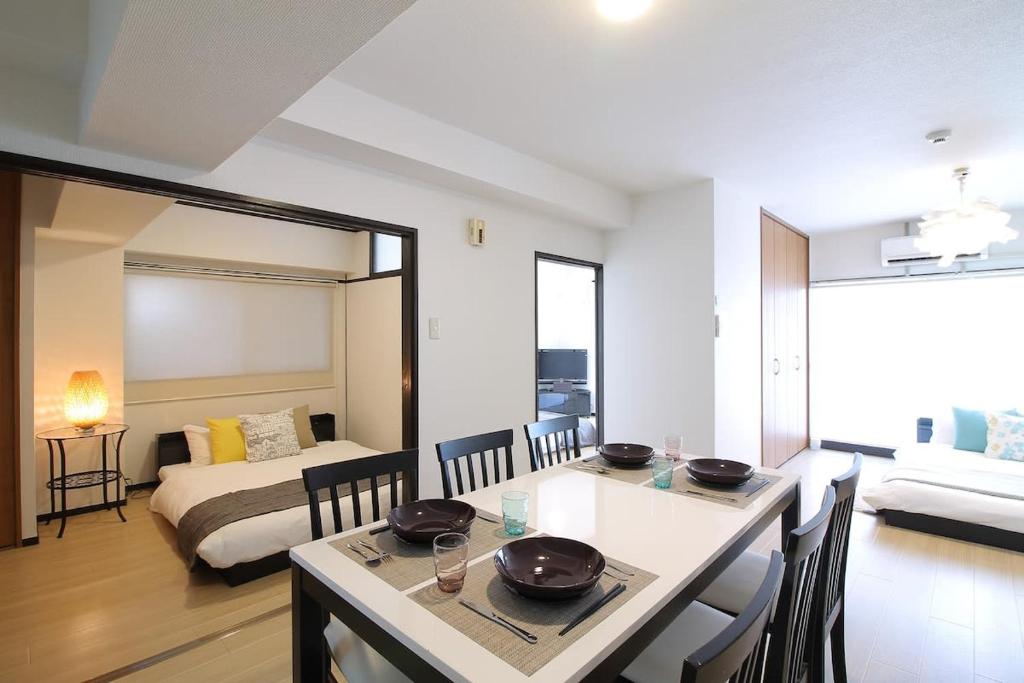 ein Wohnzimmer mit einem Esstisch und ein Schlafzimmer in der Unterkunft Mitao bld - Huge 3 bedroom Apt 4mins walk PeacePark 6ppl in Hiroshima