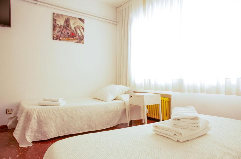 バルセロナにあるバルセロナ シティ ストリートの白い部屋で、ベッド2台、窓が備わります。