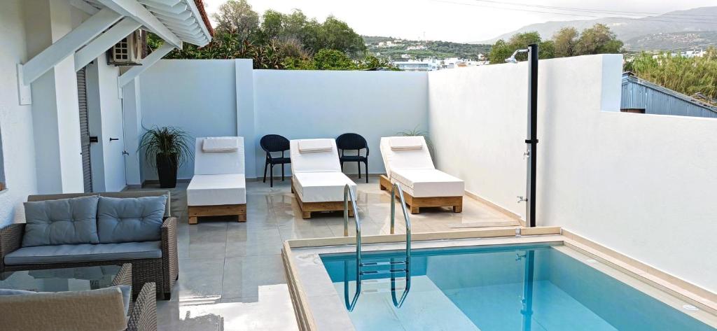 einen Balkon mit einem Tisch und Stühlen neben einem Pool in der Unterkunft Arokaria Holiday Houses in Platanes