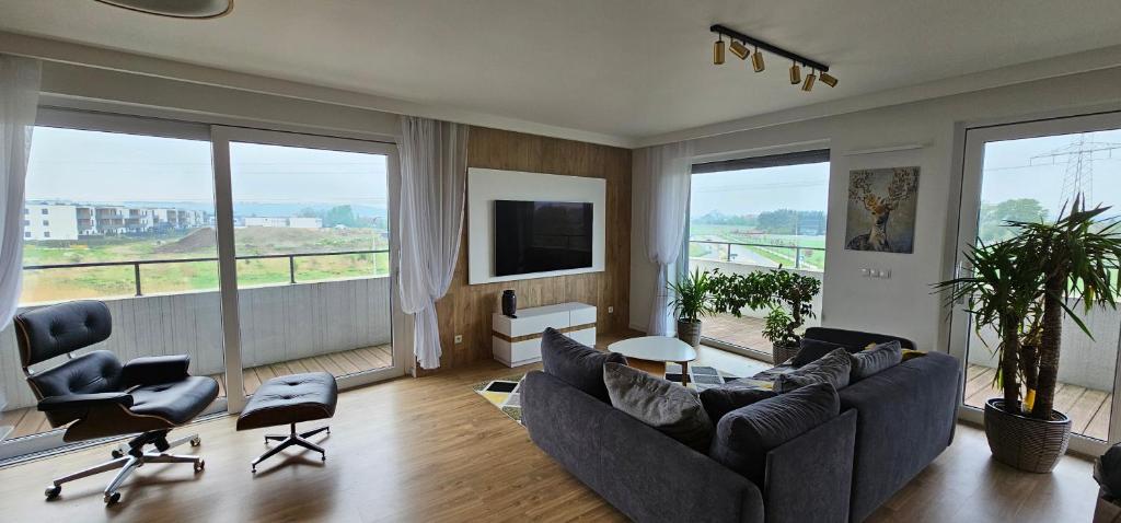a living room with a couch and chairs and windows at Apartamenty Natura in Opole