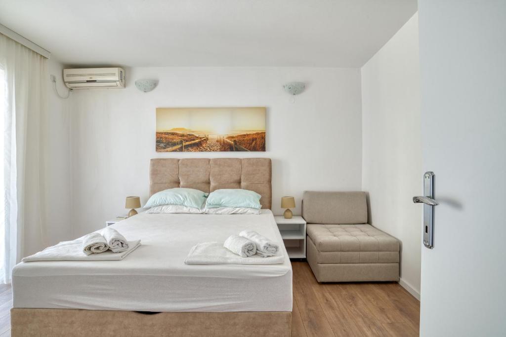 - une chambre avec un grand lit blanc et une chaise dans l'établissement Apartman Zenta, à Petrovac na Moru