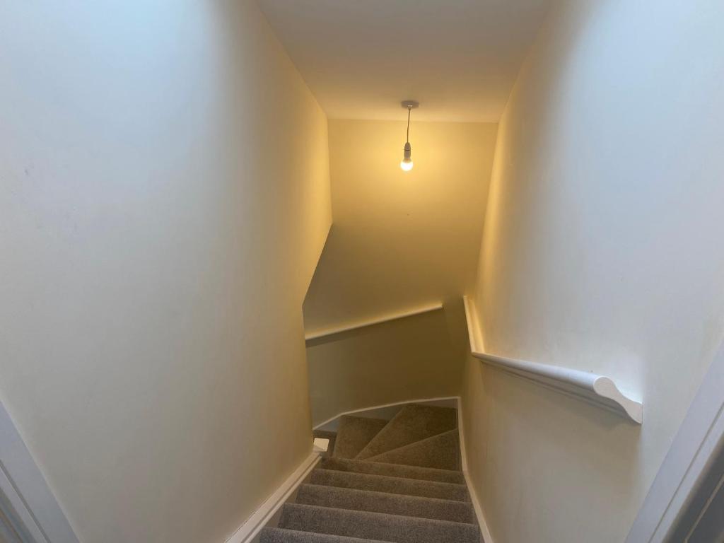 einen Flur mit Treppe mit Licht an der Wand in der Unterkunft Bath road villa in Keynsham