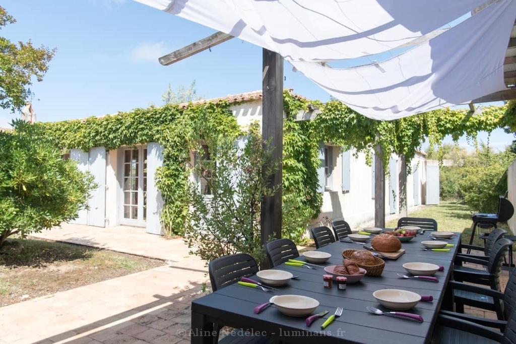 a table set up for a meal under an umbrella at Le Marais Aixois - Grande maison familiale in Île dʼAix