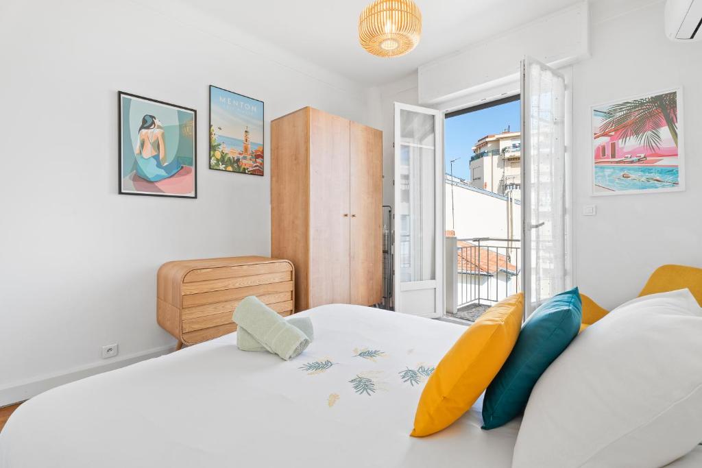 une chambre blanche avec un grand lit et une fenêtre dans l'établissement Terrasse des Oliviers, à Nice