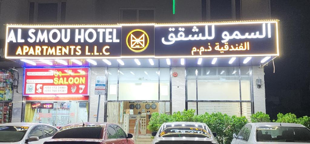 a sign for a hotel with cars parked in front at Al Smou Hotel Apartments - MAHA HOSPITALITY GROUP in Ajman 