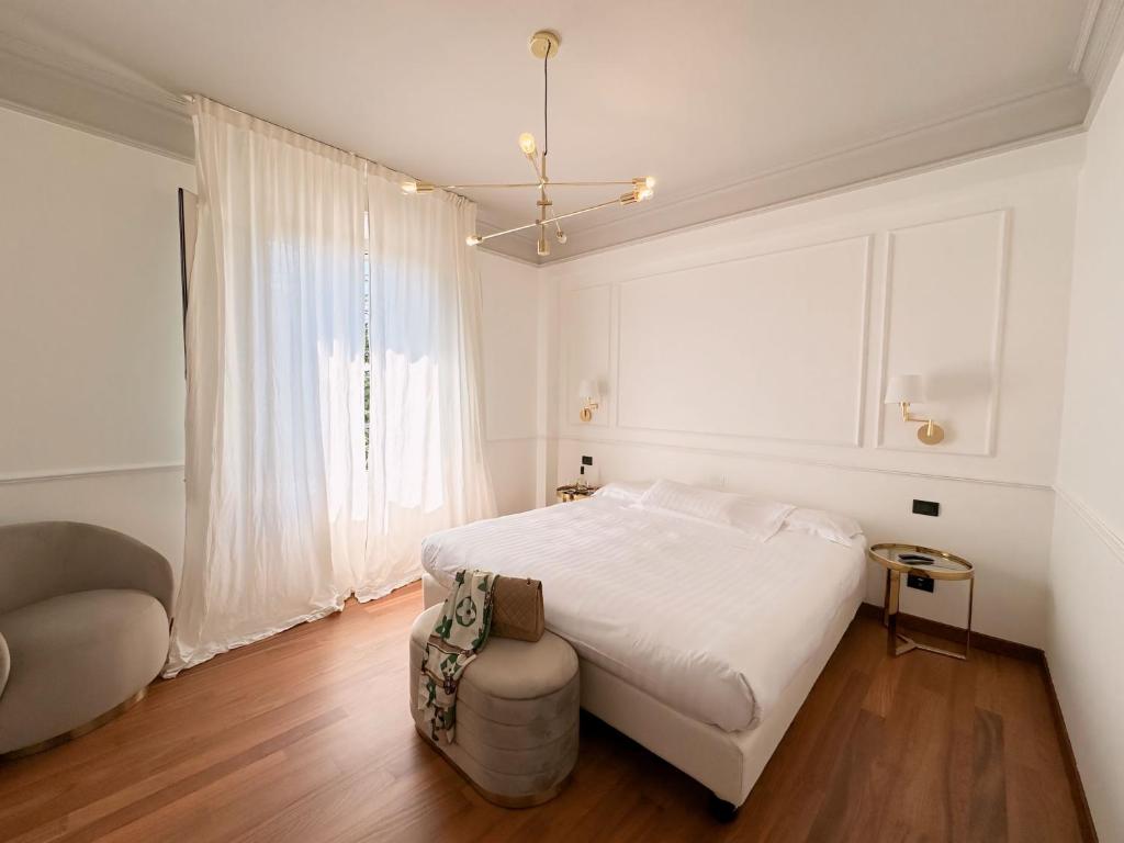 1 dormitorio blanco con 1 cama y 1 silla en Rechigi Park Hotel, en Módena