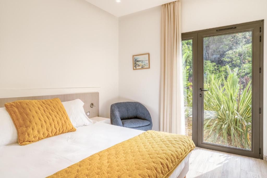 a bedroom with a bed and a chair and a window at Akwabay - Les Villas du Cap in Le Lavandou