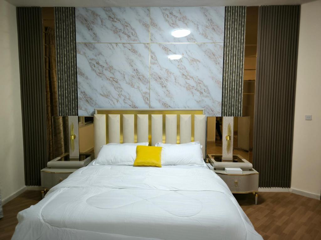 a bedroom with a white bed with a yellow pillow at شقة فخمة وواسعة غرفتين luxury and big 2BR in Ajman 