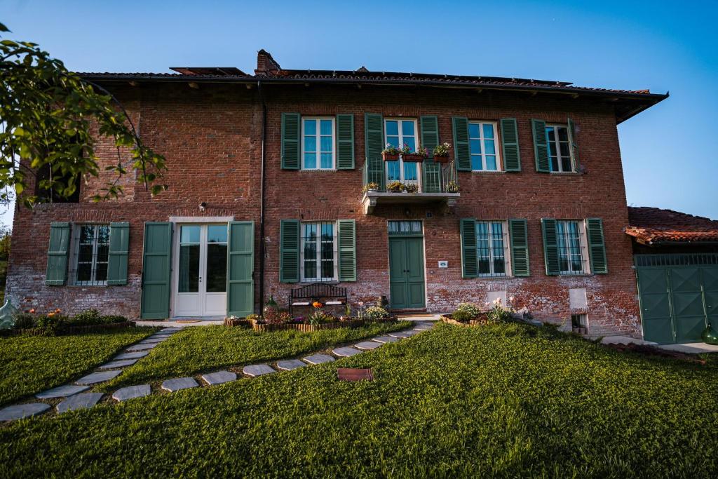 uma casa de tijolos com uma porta verde e janelas em Bed & Breakfast Barbera e Tulipani em Scandeluzza