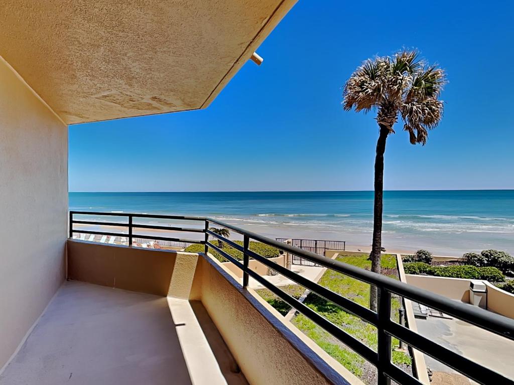 a balcony with a view of the beach and a palm tree at Oceans Atrium 205 in Daytona Beach Shores