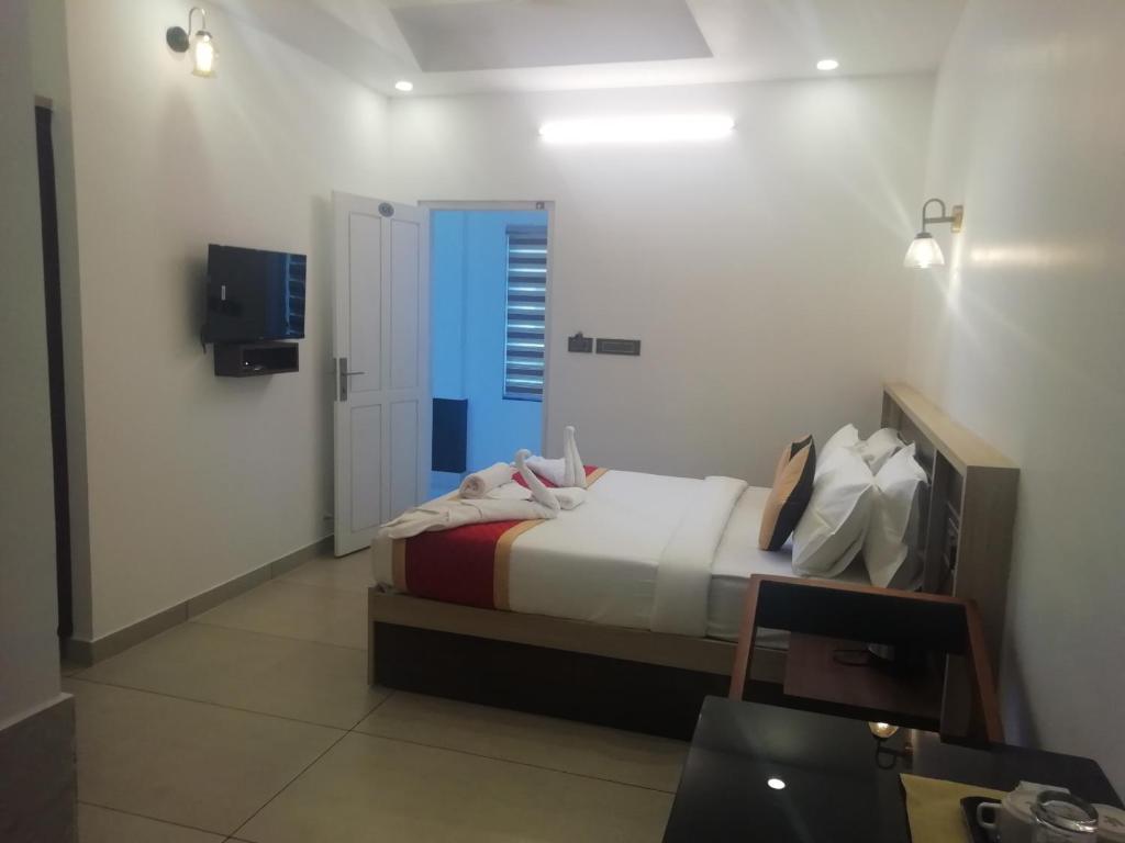 um quarto com uma cama e uma televisão num quarto em PAUL RESIDENCY em Nedumbassery