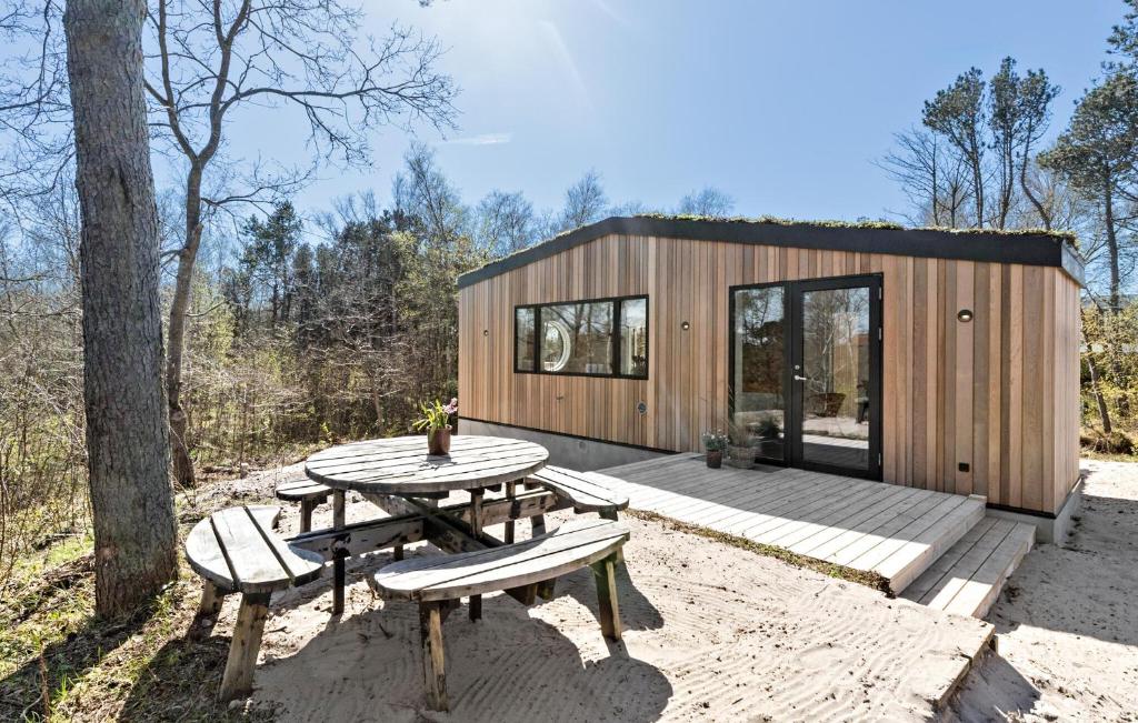 a small wooden cabin with a picnic table and benches at Amazing Home In Grenaa With Kitchen in Grenå