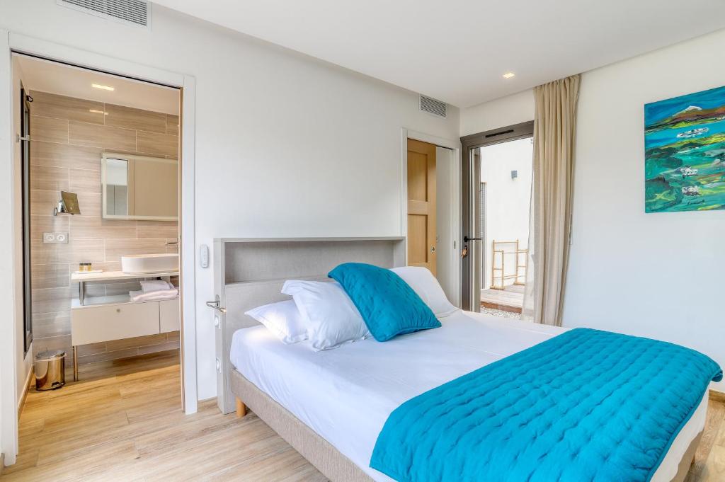 a bedroom with a large white bed with blue sheets at Akwabay - Les Villas du Cap in Le Lavandou