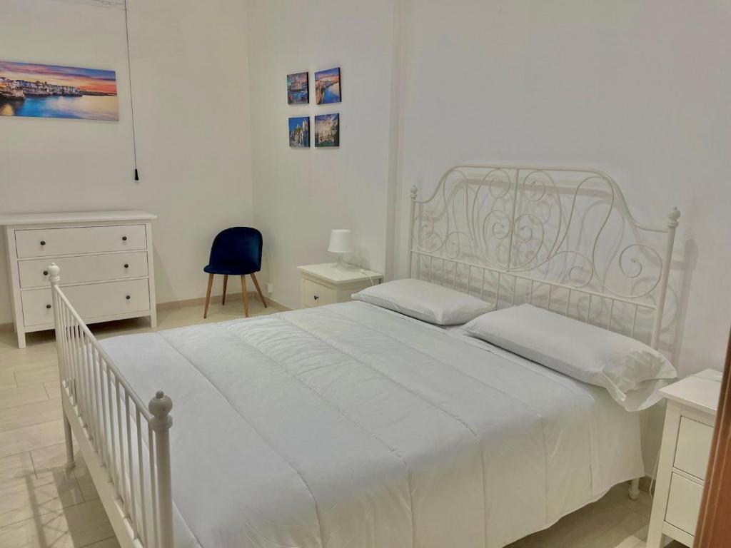 - une chambre avec un lit blanc et une chaise bleue dans l'établissement Villa vista mare, à Santo Spirito