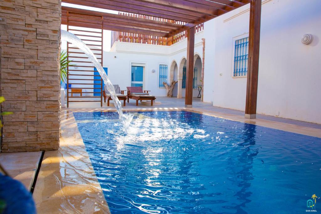 uma piscina com uma fonte numa casa em DAR AMEL em Houmt Souk