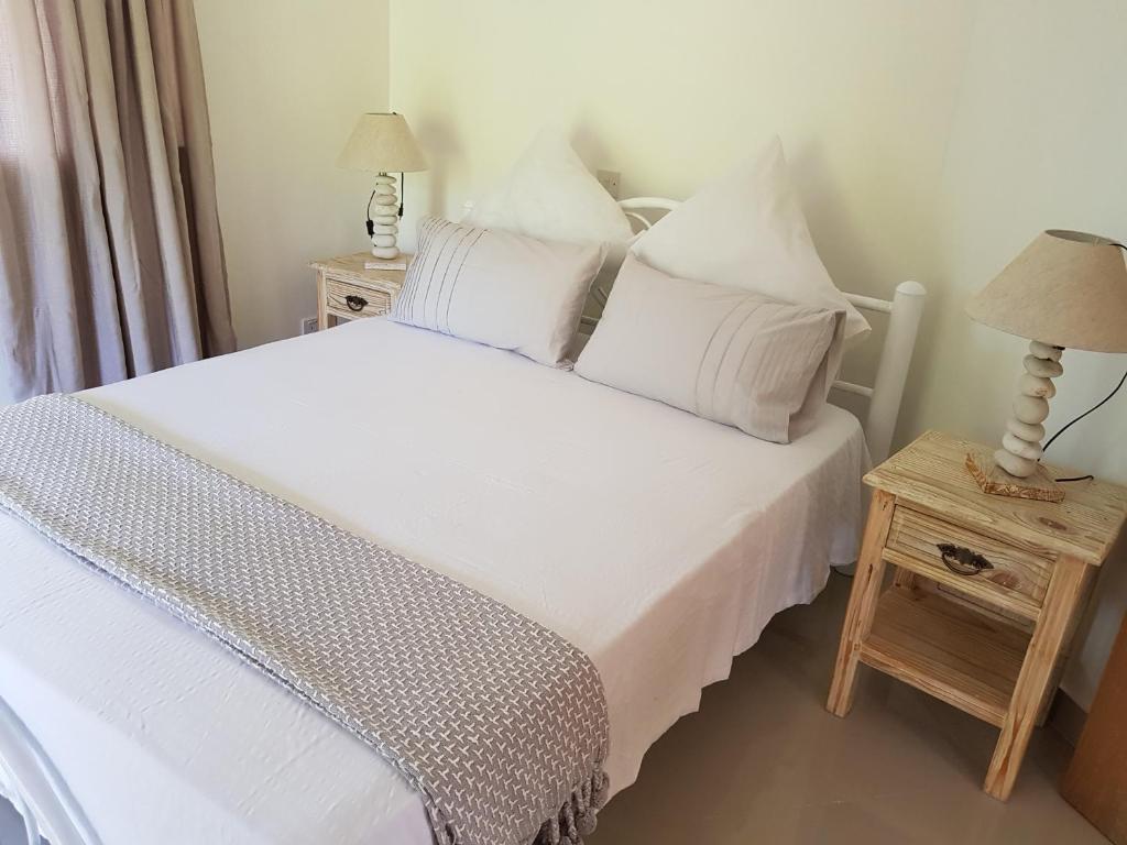 Schlafzimmer mit einem Bett mit weißer Bettwäsche und Kissen in der Unterkunft SOUTH HILL VILLA in Mahé