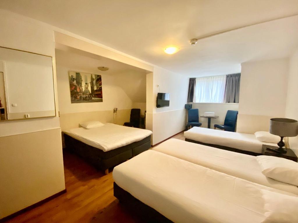 アムステルダムにあるHotel Sphinxのベッド2台とデスクが備わるホテルルームです。