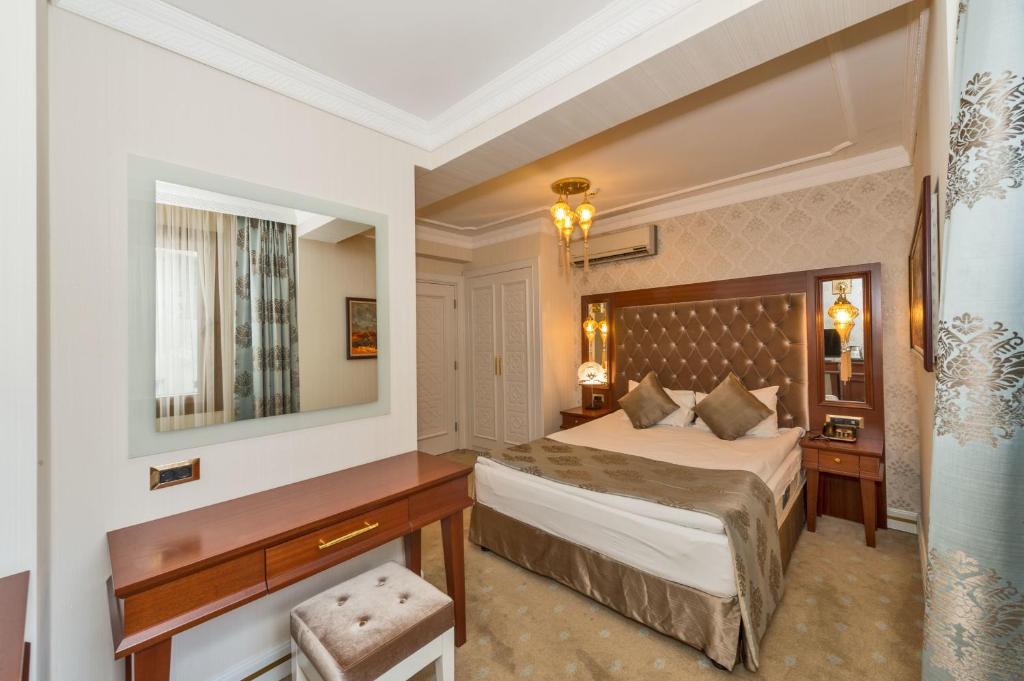 a bedroom with a bed and a desk and a mirror at The Empress Theodora Hotel in Istanbul