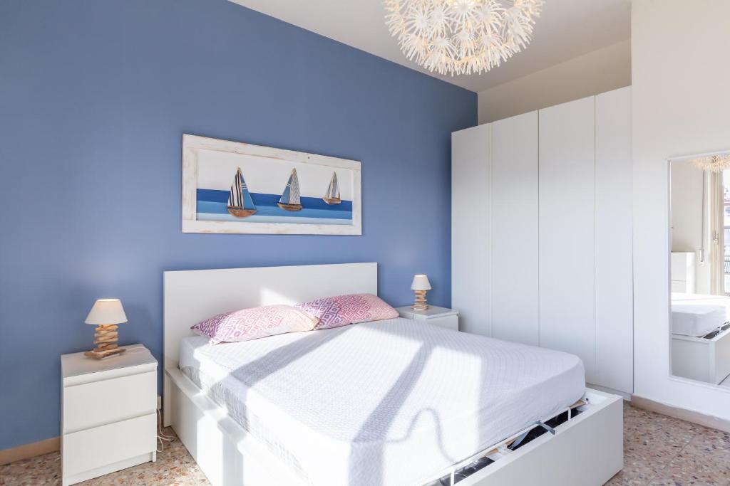 Dormitorio azul con cama y lámpara de araña en Casa di Elena Marina di Carrara, en Marina di Carrara