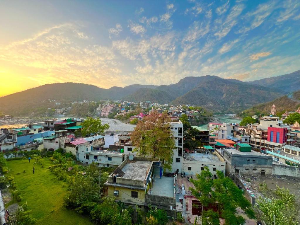 a city with a river and mountains in the background at Hotel Manikut in Rishīkesh