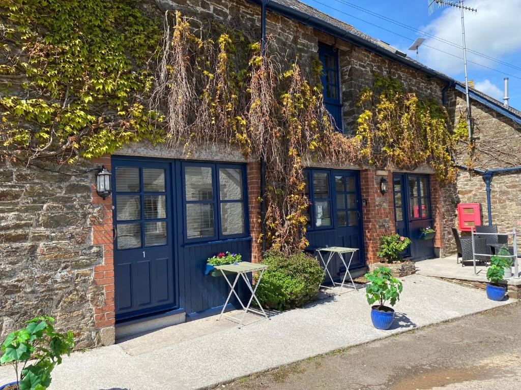 a brick building with blue doors and plants at The Ivy Barn Holbeton in Plymouth