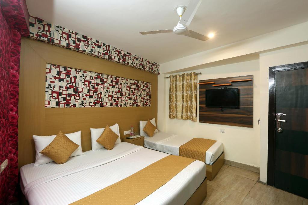 a hotel room with two beds and a flat screen tv at Hotel Sky Wood At Airport in New Delhi