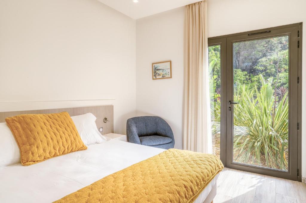 a bedroom with a bed and a chair and a window at Akwabay - Les Villas du Cap in Le Lavandou