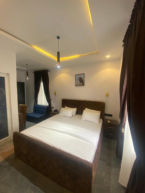 um quarto com uma cama grande e uma cadeira azul em BLUE AO HOTEL AND SUITES em Lagos
