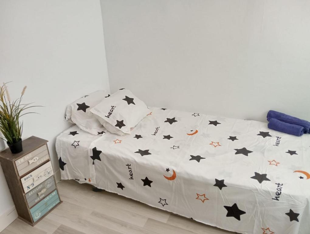 a bed with black and white comforter with stars at Alojamiento cerca de la Playa in Valencia