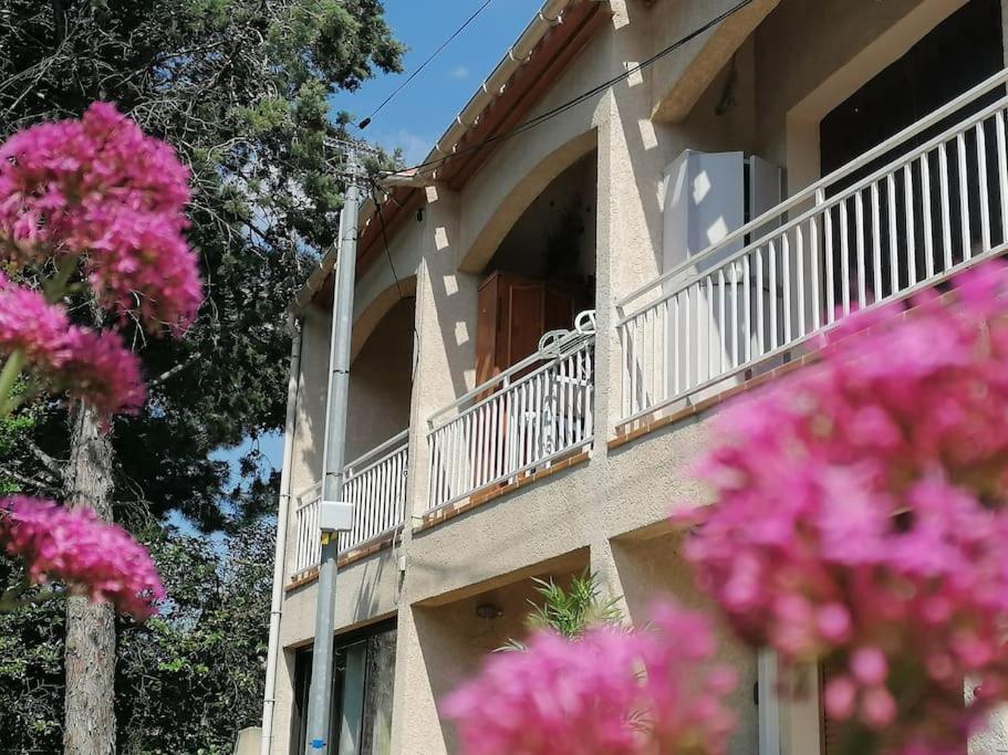 - un bâtiment avec un balcon orné de fleurs roses dans l'établissement La Franqui Appartement cozy deux chambres, à Leucate