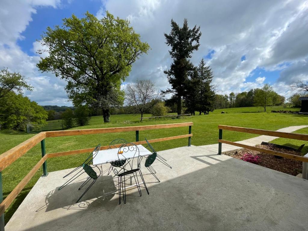 een tafel en stoelen op een veranda met een veld bij Gite Varagnac in Saint-Cyr-les-Champagnes
