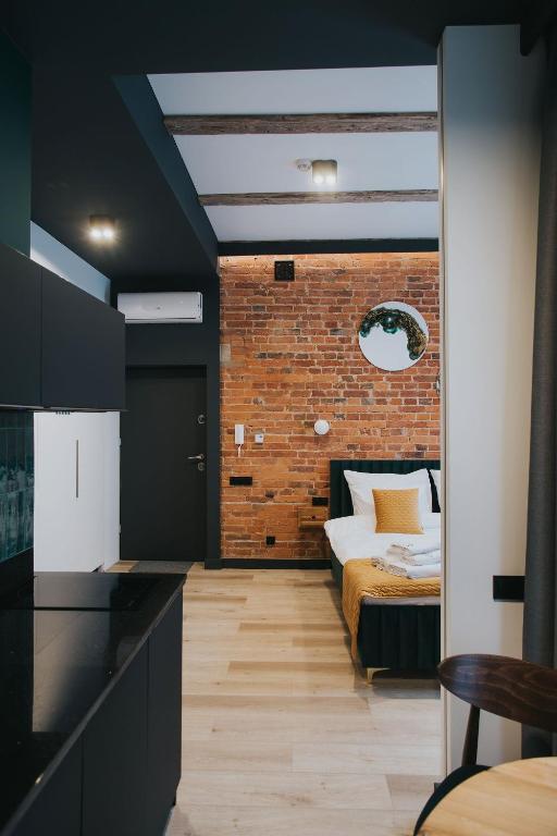 a bedroom with a bed and a brick wall at BIBLIO Apartamenty in Łódź