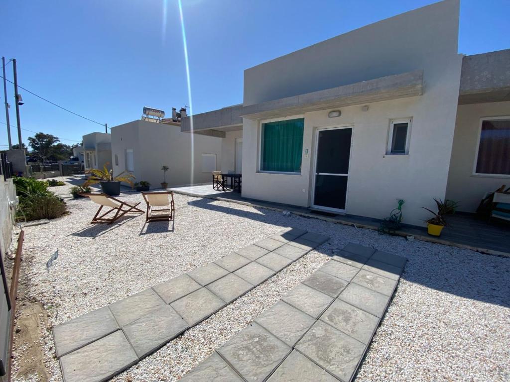 a patio with two chairs in front of a building at SUN KISS HOUSES Sun Kiss Houses B in Áyios Spirídhon